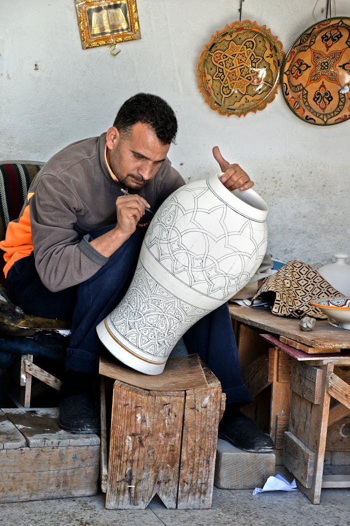 Artisan in Fès, Morocco intricately designs a large clay vase, showcasing traditional craftsmanship.