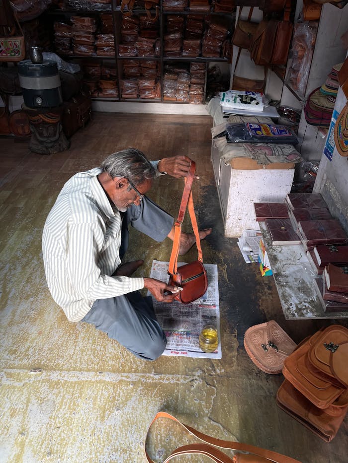 Artisan crafting leather goods in a traditional Jaisalmer shop, India.